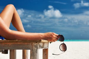Woman at beautiful beach holding sunglasses - Maison d'Azur. C'est l'été !